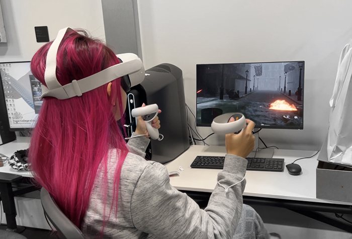 A playtester wearing a VR headset, controllers raised, in front of the flooded Westminster game world