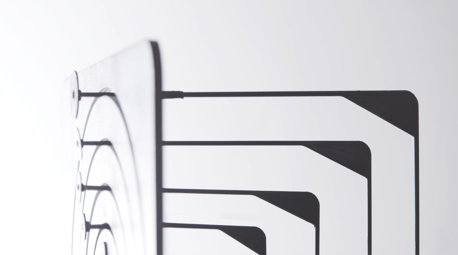 A close-up of the device's front face at a raking angle: concentric laser-cut rings standing proud of a white panel, each with its own shadow