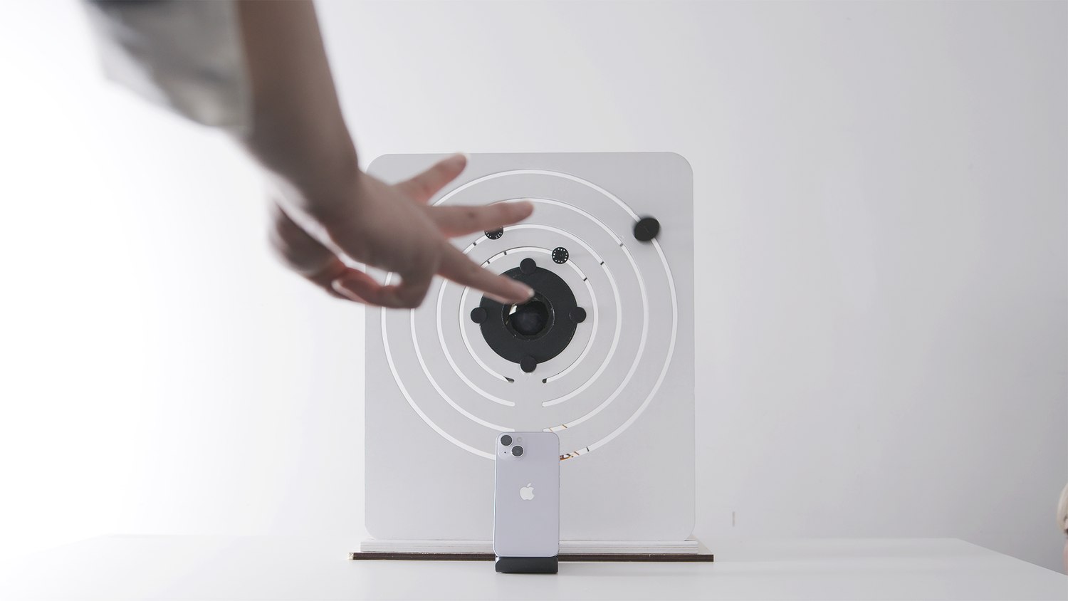 A hand with two fingers extended in front of the device, another ring rotated