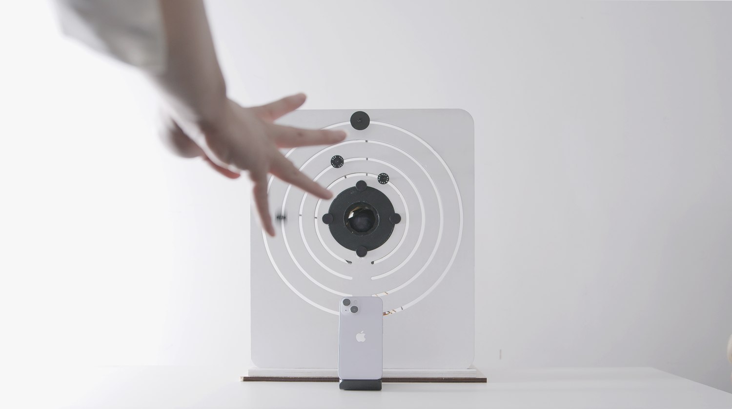 A hand with fingers spread in front of the device, several ring markers now at their target angles