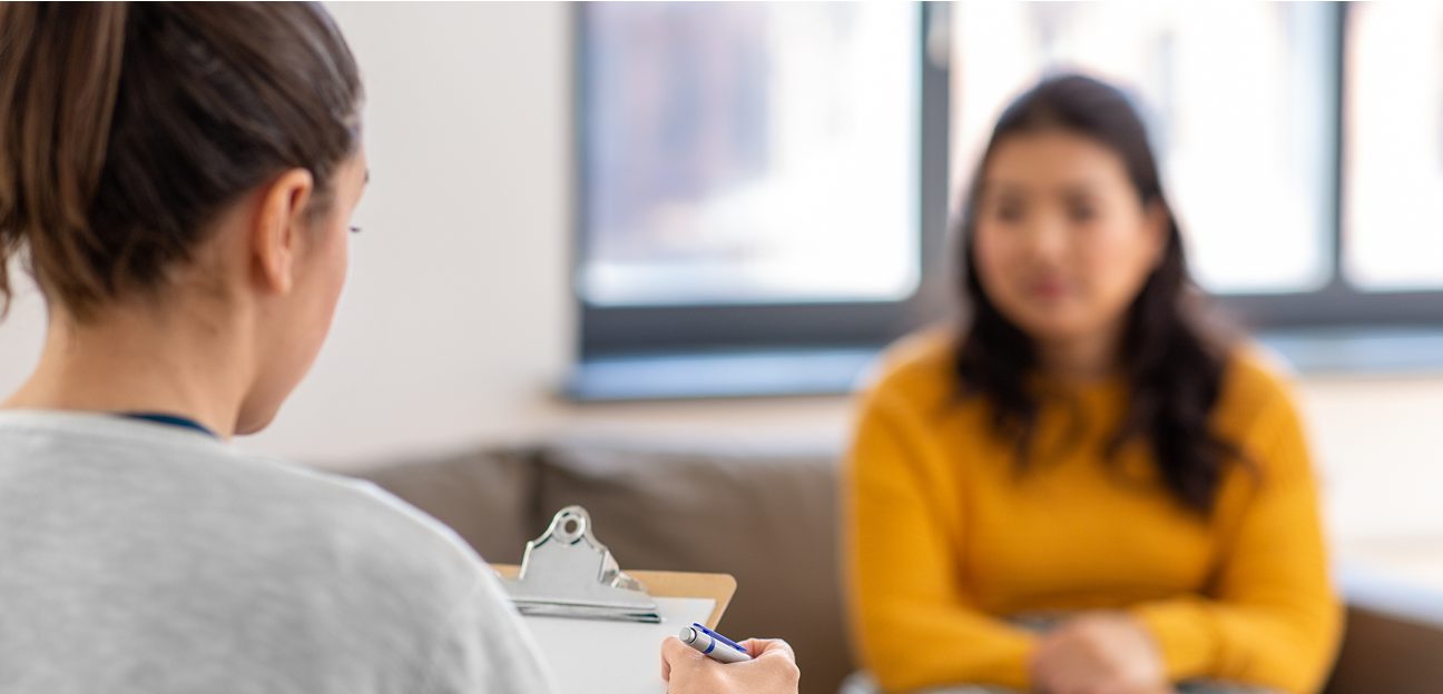 A clinician takes notes during a consultation with a patient