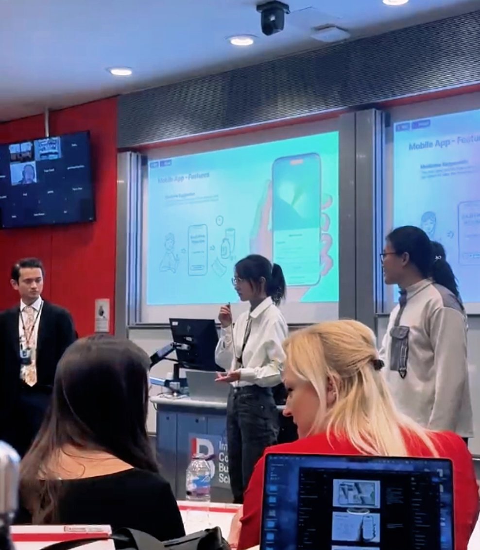 The team pitching RES in a lecture theatre at Imperial College Business School, with a 'Mobile App — Features' slide showing the app on screen behind them and an audience seated in front