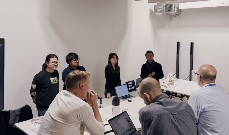 The four-person RES team presenting to a seated review panel: the team standing beside a laptop showing their slides, with reviewers seated at the table in front of them