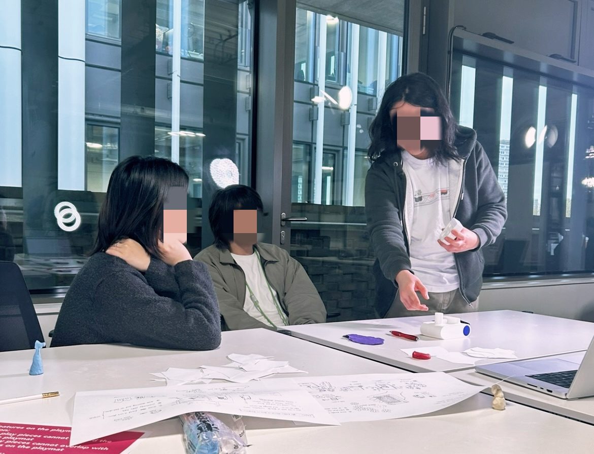 A user workshop in progress: participants around a table covered in worksheets and sketches, with a facilitator holding a prototype of the RES sensor