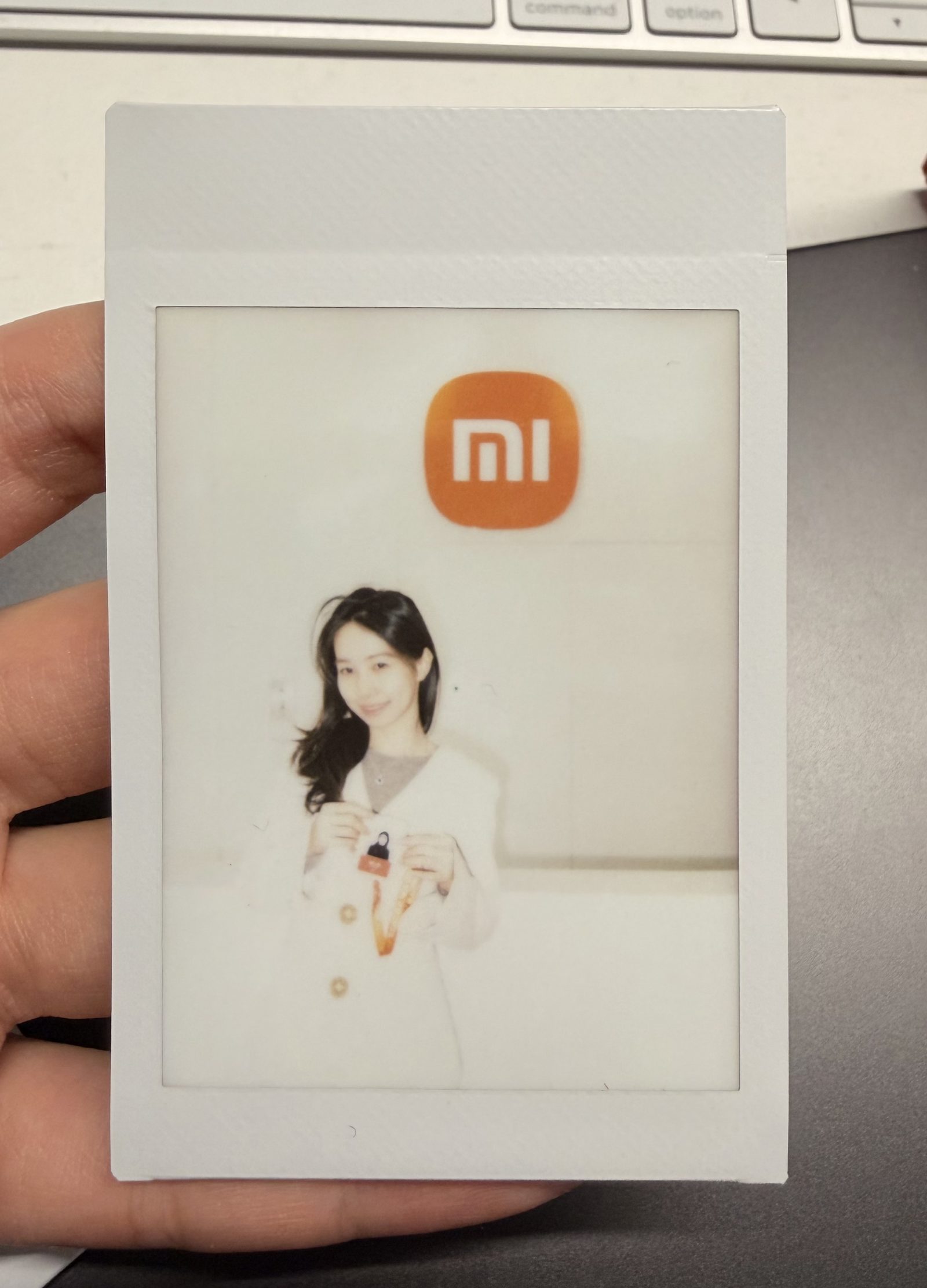 A Polaroid-style photo of Yidan Xu holding a small Xiaomi keychain during her time as HMI designer on the Xiaomi Auto team