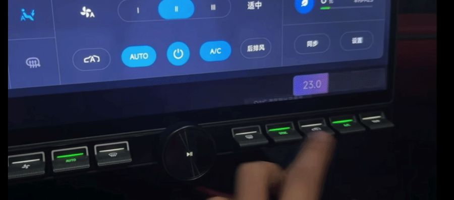 A finger pressing along the physical key strip at night. On the screen above, the bar answers each press: the temperature reads 23.0, and a message confirms that the temperature zones have been synced