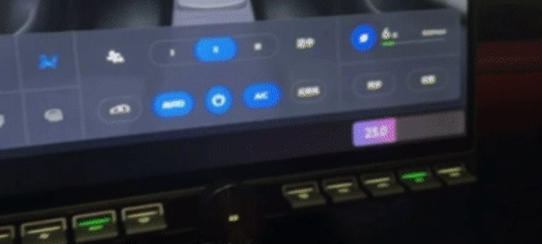 A hand at the right end of the physical strip. On the screen the passenger's temperature falls, highlighted on the right-hand side, and a message confirms the two zones have been synced